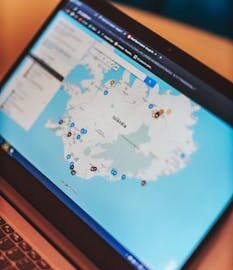 From above of open netbook with geographic map and bright symbols on web page